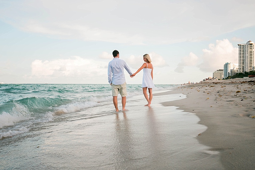 two people holding hands walking on the beach